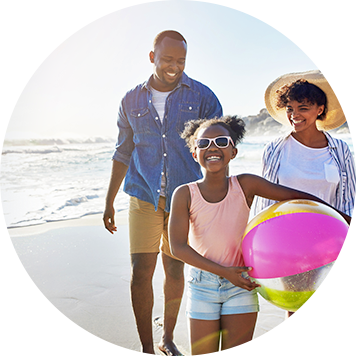 Dad, mom and daughter holding a beach ball while enjoying a walk on the beach